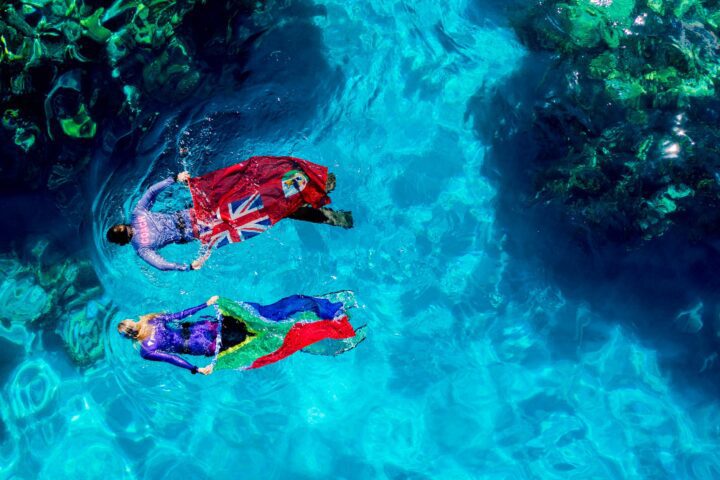 people in swimwear holding flags swimming in water