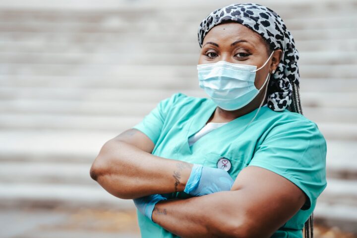 self confident black doctor with folded arms on urban stairs