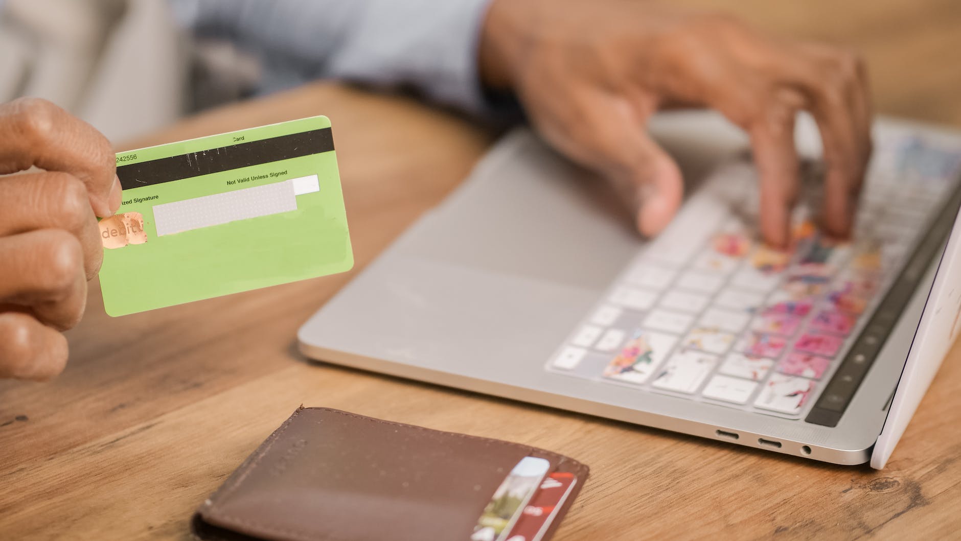 person holding green card while using silver laptop