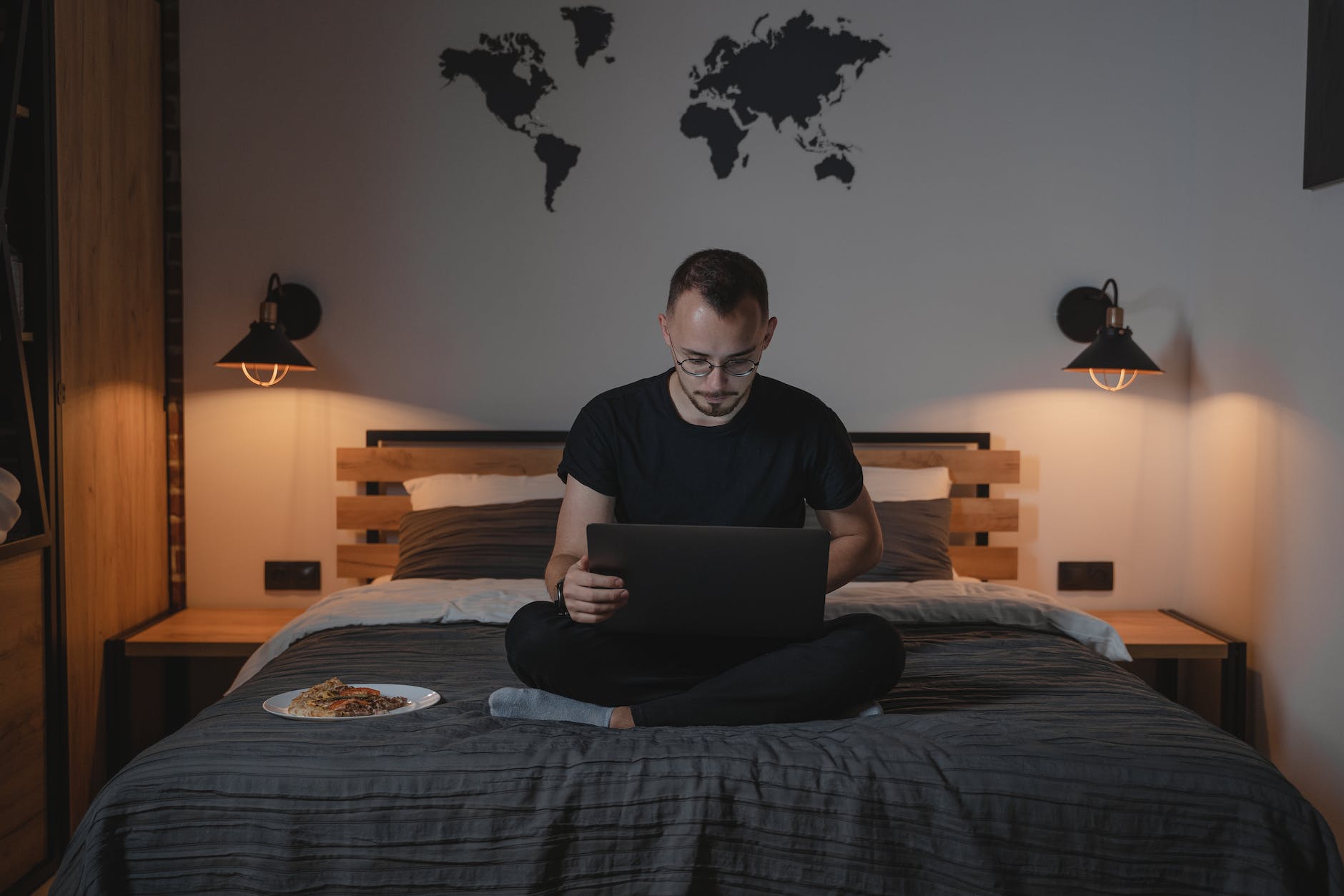 a man using a laptop while sitting on a bed