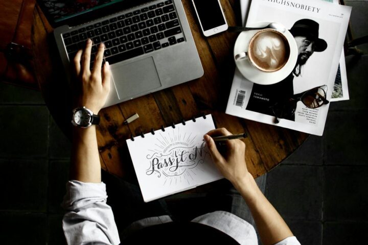 person sitting facing laptop computer with sketch pad