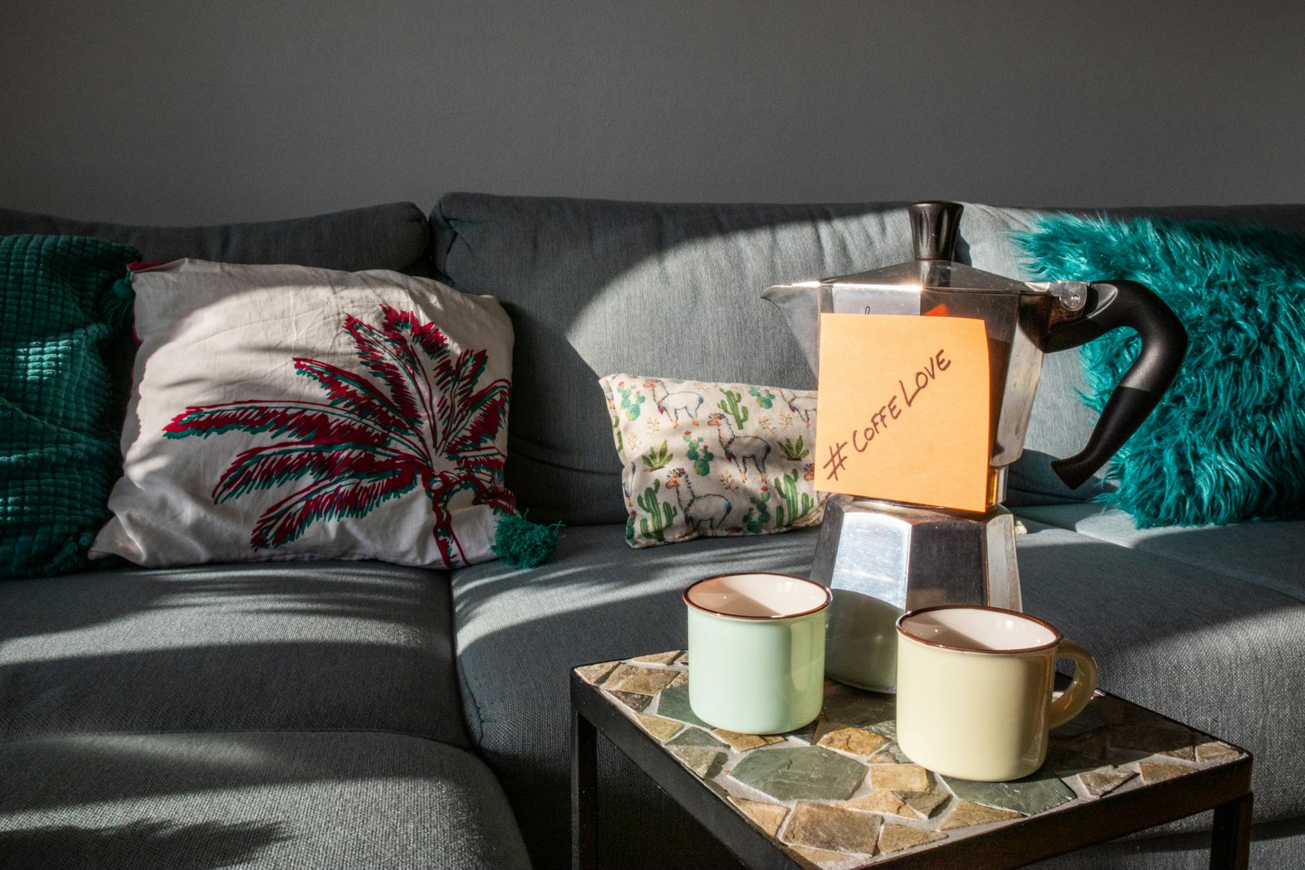 sofa with cushions and cups on a coffee table with hashtag coffee love