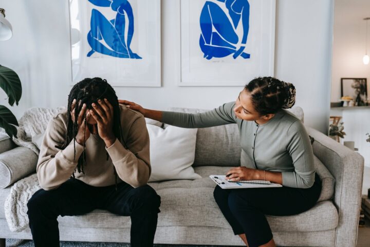 black woman consoling anonymous unhappy boyfriend on sofa at home