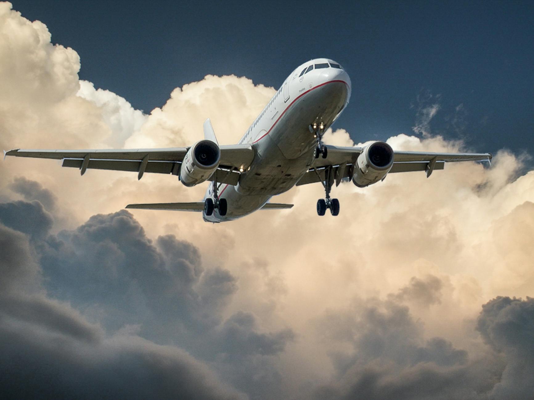 white and red plane beside clouds low angle photography