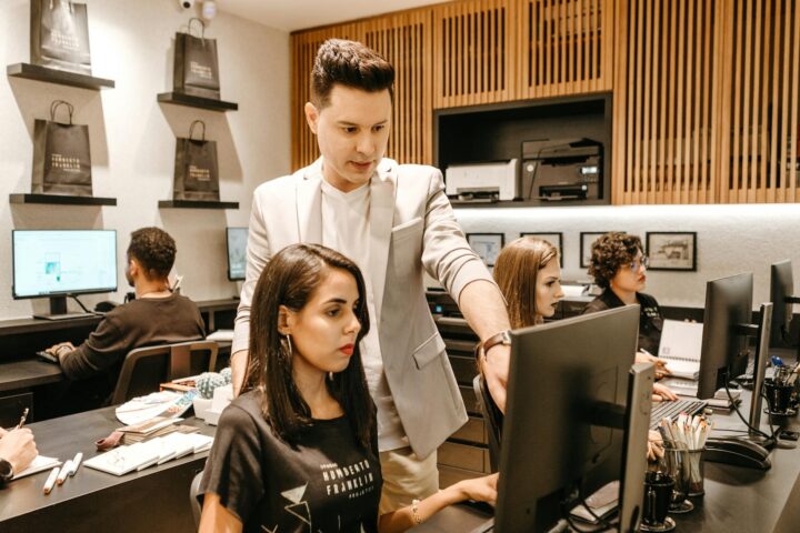 man teaching woman in front of monitor