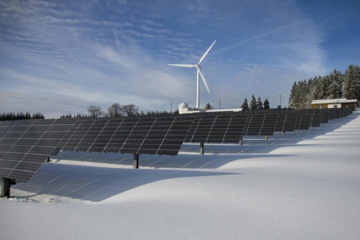 solar panels on snow with windmill under clear day sky