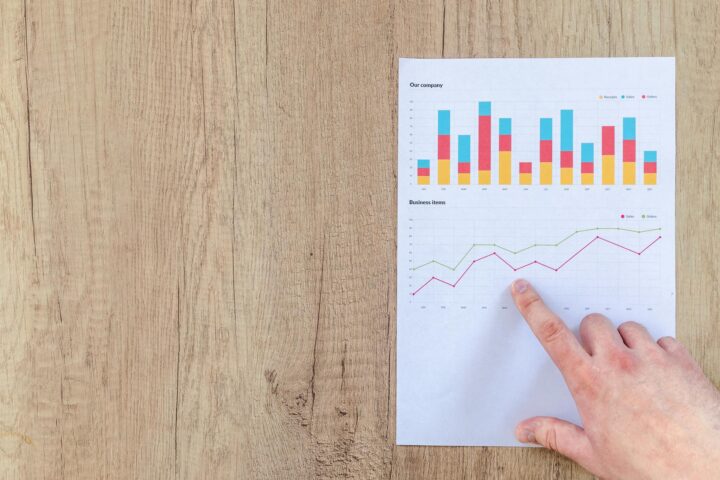 person pointing paper line graph